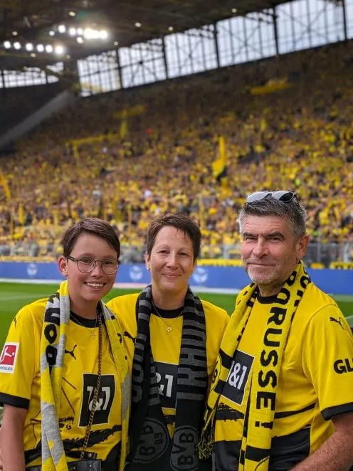Eine Jugendliche mit ihren Eltern im Dortmunder Stadion vor der gelben Wand